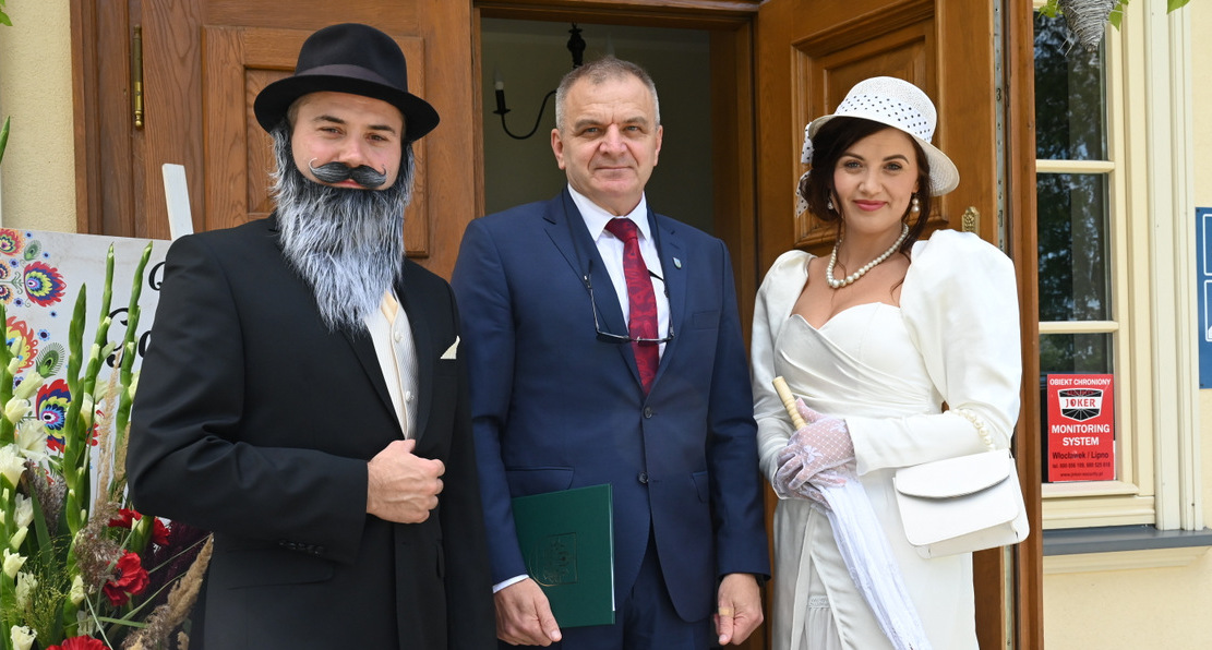 Trzy osoby stoją przed budynkiem...