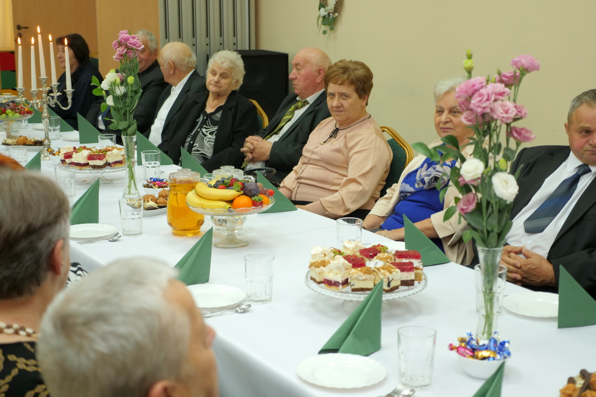 Jubilaci zasiadających przy stołach...