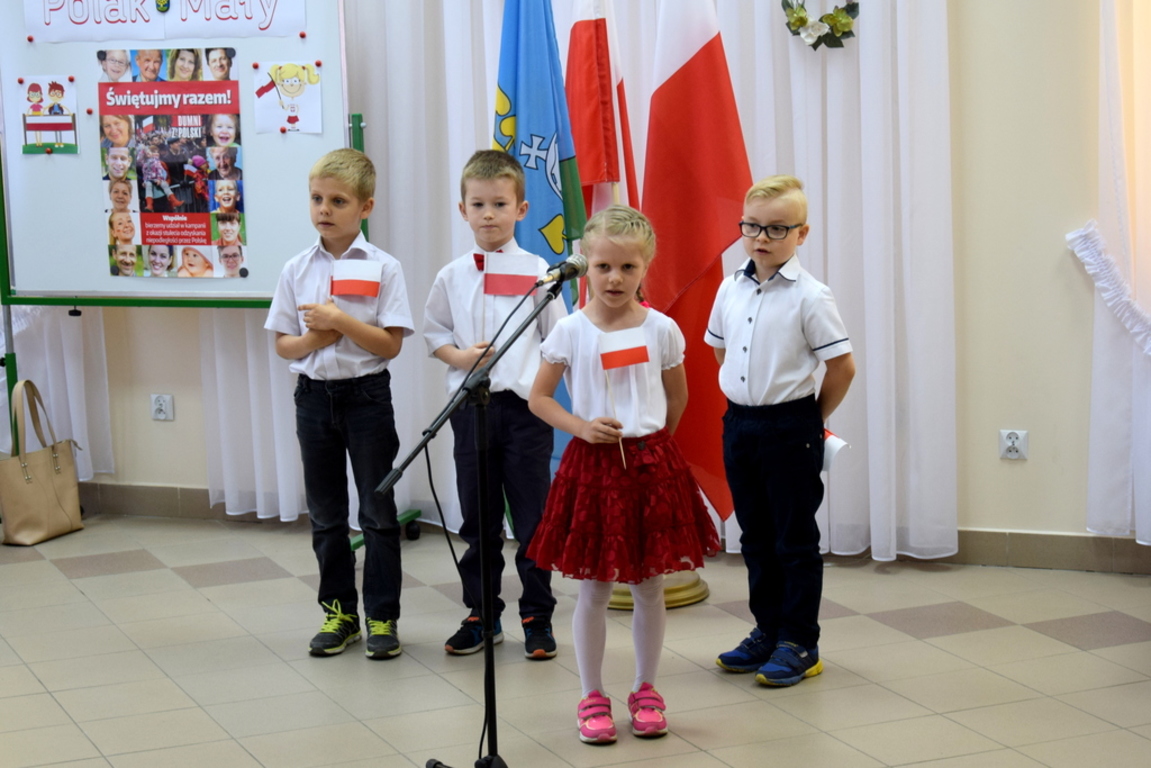 Przedszkolak z flagą polski przy mikrofonie przemawia do zebranych