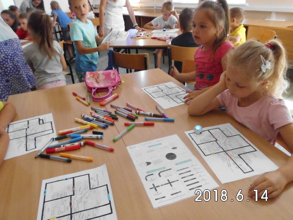 Dzieci w ławkach programujący program na kartkach papieru