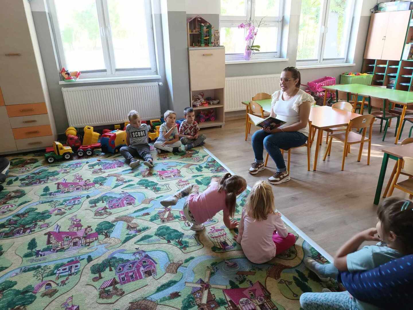 Bibliotekarka czyta dzieciom książkę poświęconą Mikołajowi Kopernikowi