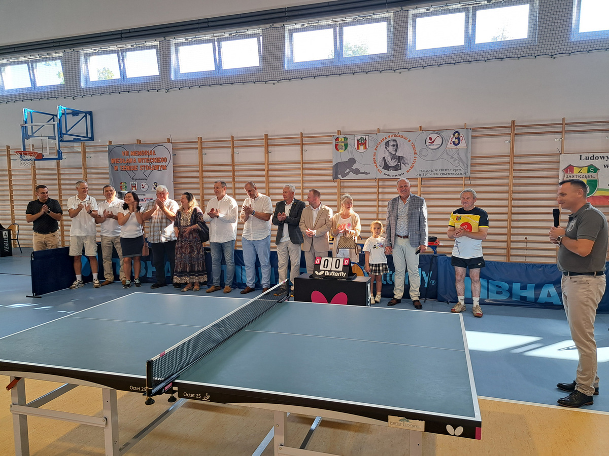 Osoby stojące w rzędzie podczas przemowy organizatora