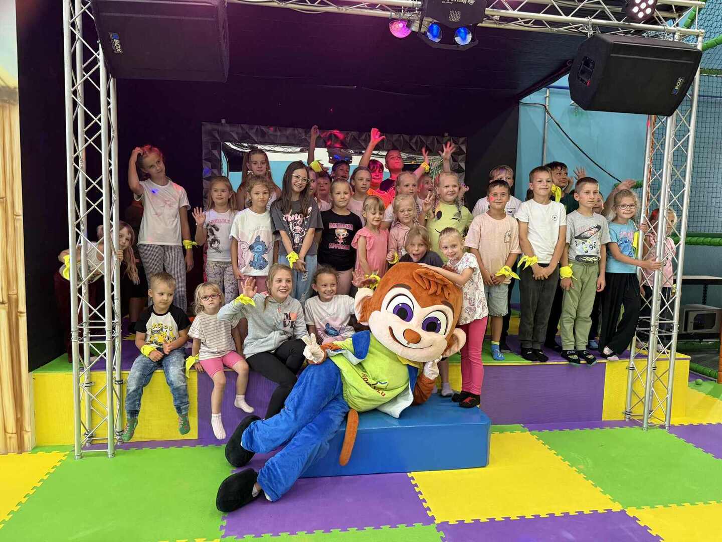 Zdjęcie grupowe uczestników wycieczki, na pierwszym planie duża maskotka