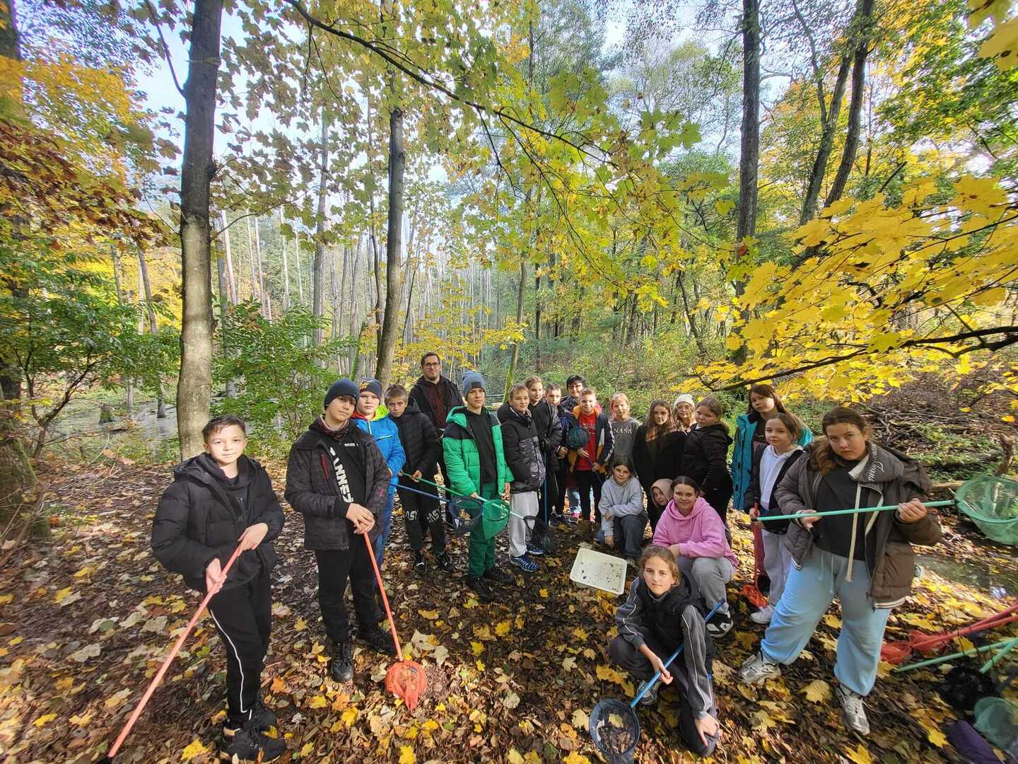Grupa uczniów pośród drzew.