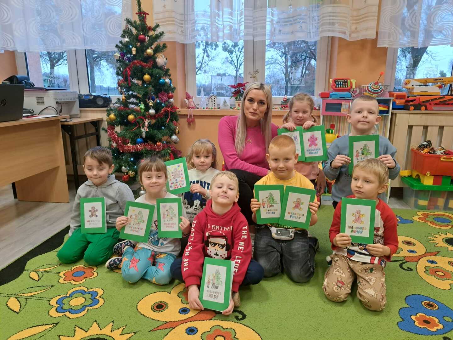 Dzieci z bibliotekarką prezentują świąteczne kartki