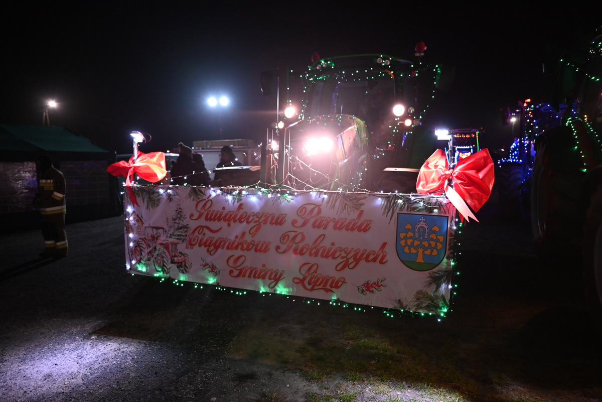 Ciągnik przy scenie w tle rozstawiony kiermaszy podczas jarmarku.