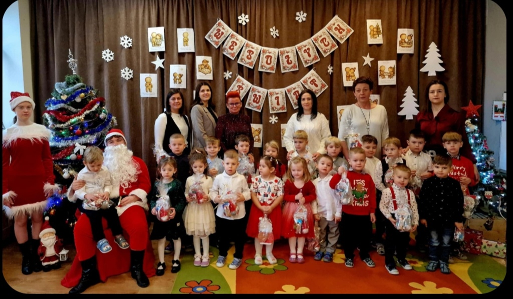 Dzieci z przedszkola pozują do wspólnego, świątecznego zdjęcia razem ze swoimi wychowawczyniami, logopedką i bibliotekarką.