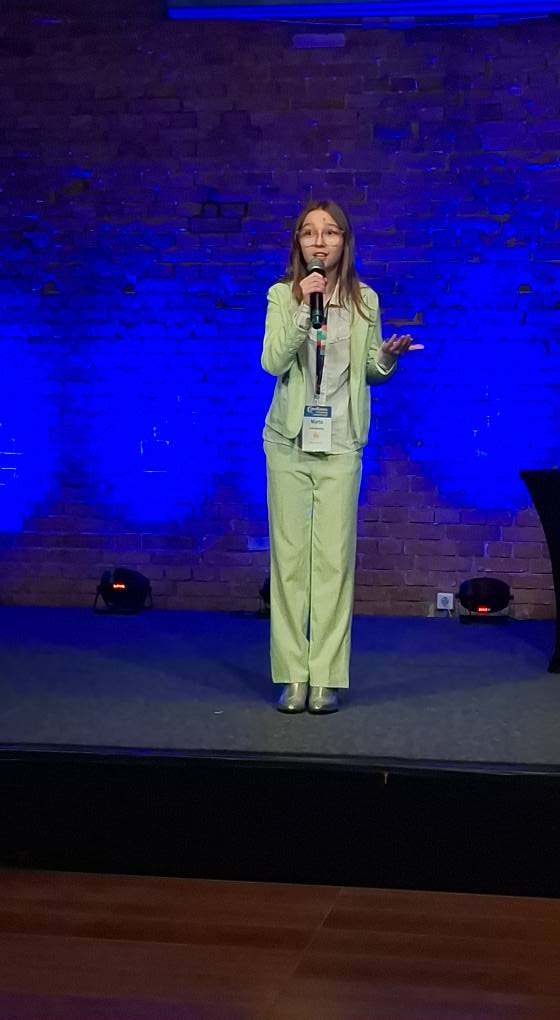 Dziewczynka w zielonym garniturze recytuje wiersz.