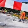 Zdjęcie przedstawia robotników remontujących chodnik.