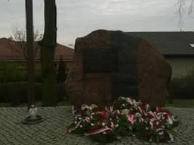 Pomnik Ofiar Katyńskich ze złożonymi pod nim wiązankami kwiatów