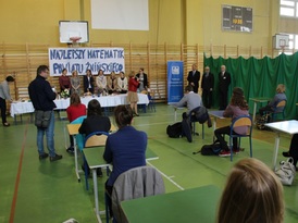 Uczniowie siedzący w ławkach szkolnych przed konkursem