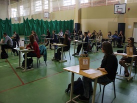 Uczniowie siedzący w ławkach szkolnych przed konkursem