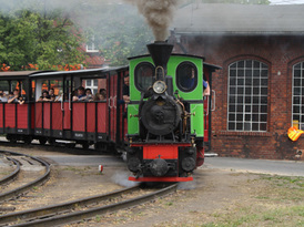 Parowóz wyruszający w podróż z wypełnionymi turystami wagonami