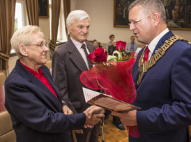 Burmistrz Żnina wręcza bukiet kwiatów jubilatom