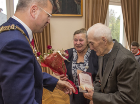 Burmistrz Żnina wręcza bukiet kwiatów jubilatom