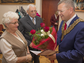 Burmistrz Żnina wręcza bukiet kwiatów jubilatom