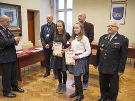 Wyróżnione w konkursie dziewczyny trzymające dyplomy z władzami Miejsko-Gminnego ZOSP, kierownikiem