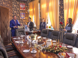 Burmistrz składa gratulacje opiekunowi nauczyciela i wręcza drobny upominek z gadżetami gminnymi