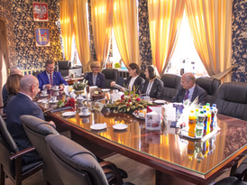 Przybyli goście siedzą przy stole na poczęstunku w gabinecie burmistrza