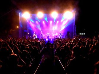 Koncert zespołu muzycznego ukazujący kolorowe światła i wizualizacje towarzyszące występującemu zesp