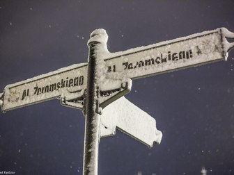 Słup z nazwami ulic pokryty śnieżnym puchem.