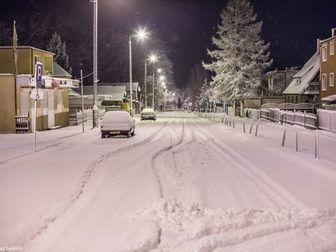 Ulica Sportowa wieczorową zimową porą, pokryta śnieżnym puchem.