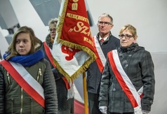 Delegacja NSZZ Solidarność wraz ze sztandarem i polskimi szarfami, uczestnicząca we mszy świętej.