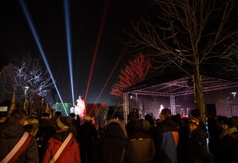 Uczestnicy uroczystości, a w tle rozświetlony pomnik Generała.