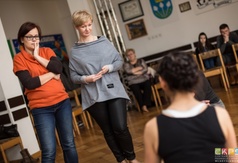 Uczestnicy spoglądający na prowadzącą w trakcie ćwiczeń podczas warsztatów teatralnych.