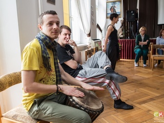 Mężczyzna grający na bębnie, prowadząca oraz uczestnicy w trakcie ćwiczeń podczas warsztatów teatral