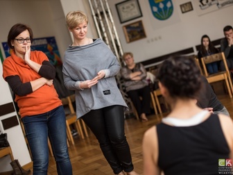 Uczestnicy spoglądający na prowadzącą w trakcie ćwiczeń podczas warsztatów teatralnych.
