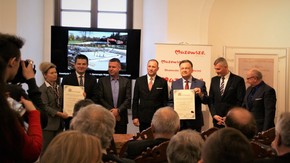 uczestnicy uroczystości pozują do zdjęcia z podpisanymi aktami erekcyjnymi
