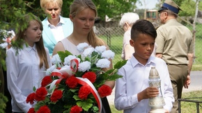 uczniowie składają kwiaty pod obeliskiem