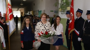 Dyrektor Małgorzata Jakubowska wraz z uczniami składa kwiaty pod tablicą upamiętniającą patrona szko
